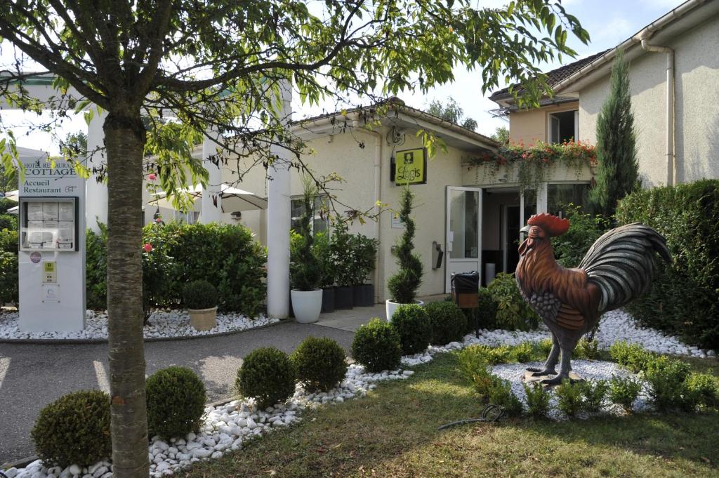 una estatua de un pollo delante de una casa en Logis Cottage Hotel en Vandoeuvre-lès-Nancy