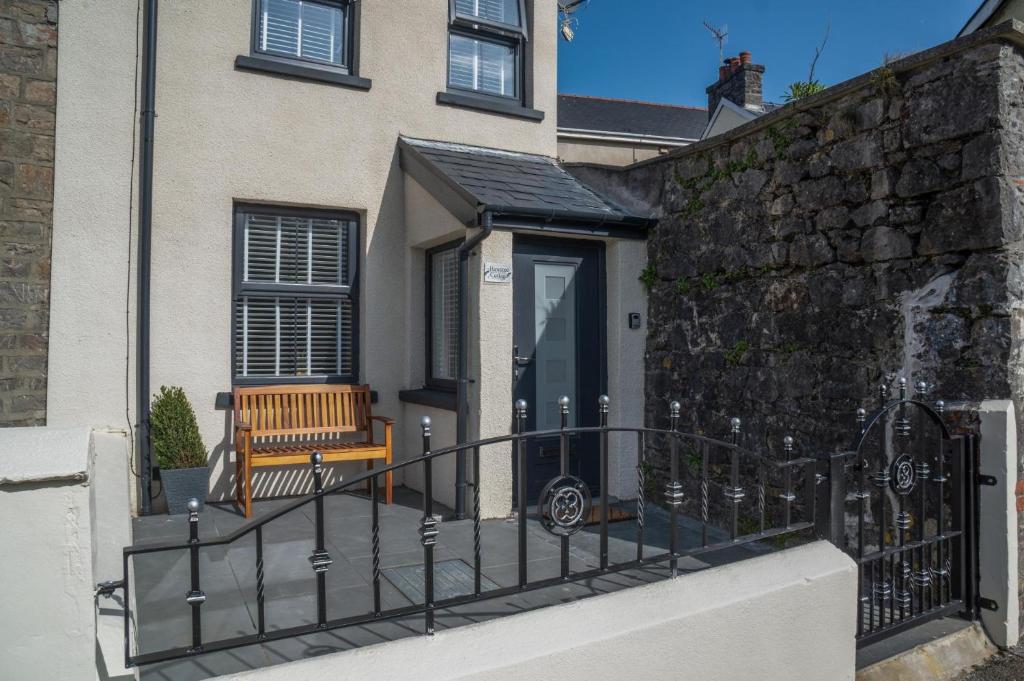 a house with a fence and a bench in front of it at Hawtree Cottage - 2 Bedroom Cottage - Tenby in Tenby