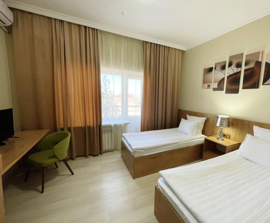 una camera d'albergo con 2 letti e una scrivania di Aktau Airport Hotel ad Aqtau