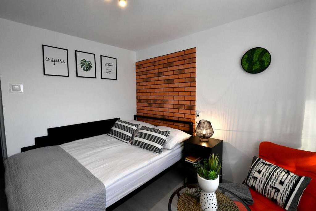 a bedroom with a bed and a brick wall at Apartament - Spytkowice in Spytkowice