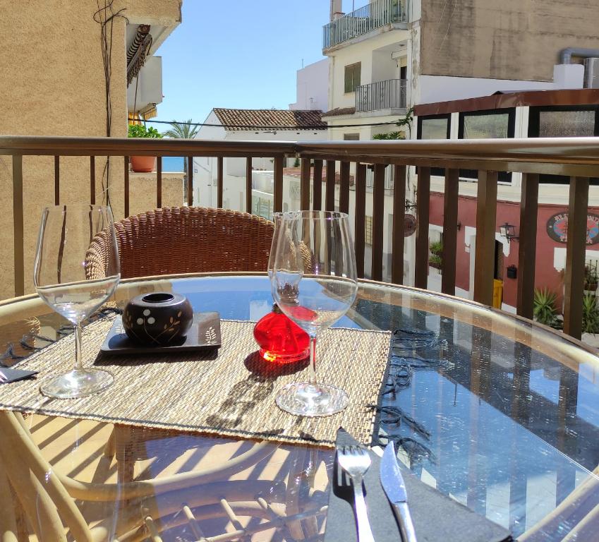 un tavolo con 2 bicchieri da vino sul balcone di Apartamento L 'Altina a 40 metros de la playa ad Alcossebre
