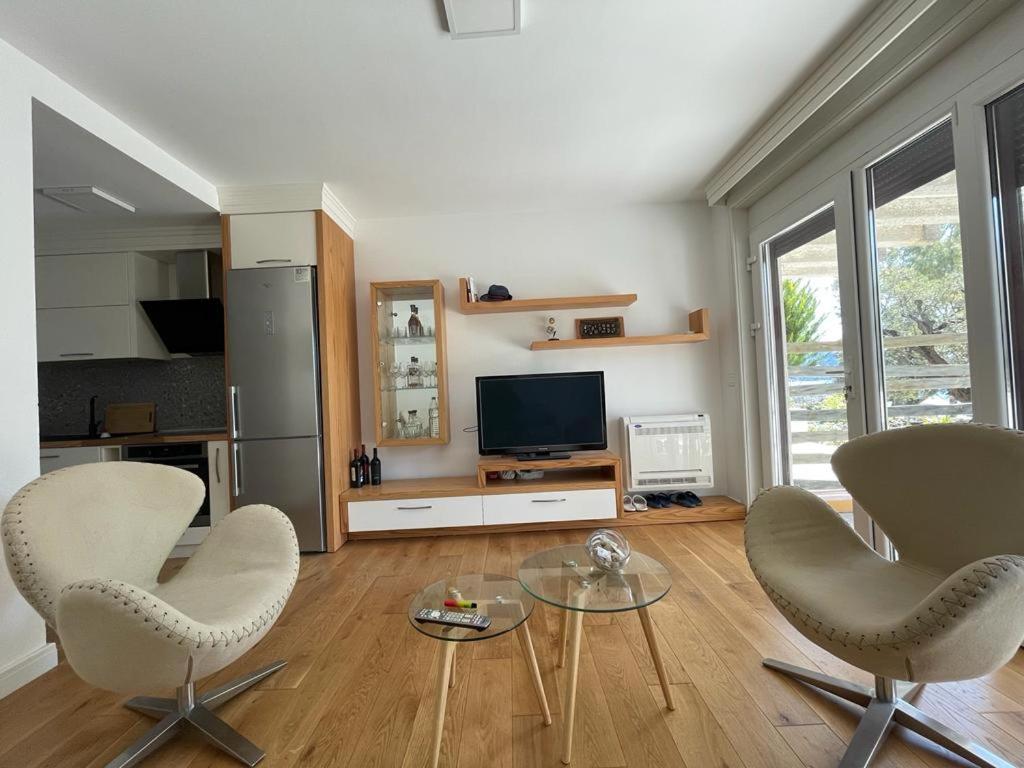 a living room with two chairs and a television at Sea Gem Apartment in Dhërmi