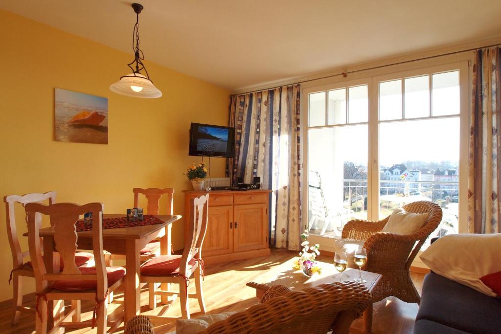 ein Wohnzimmer mit Tisch und Stühlen und einem Fenster in der Unterkunft Meeresblick Wohnung 408 in Kühlungsborn