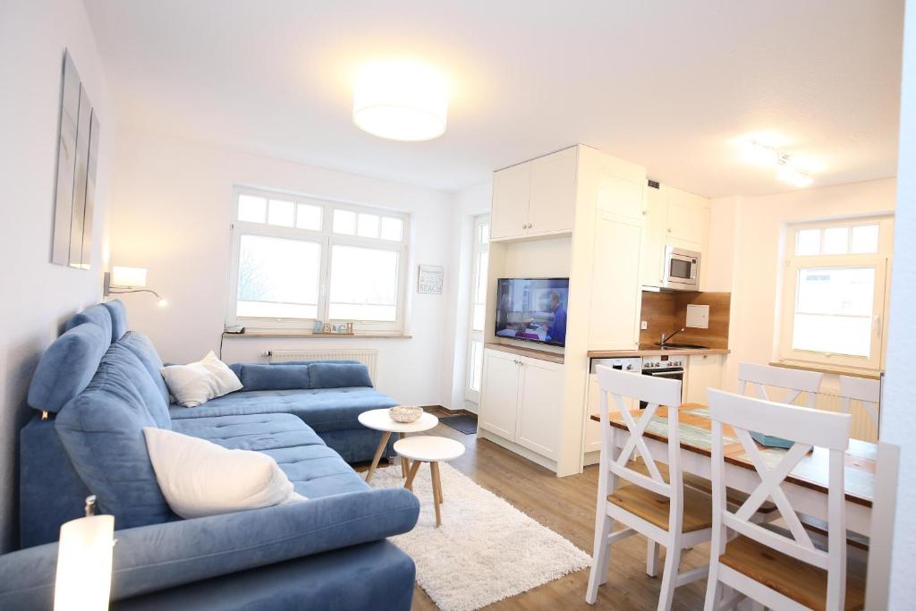 uma sala de estar com um sofá azul e uma cozinha em Villa Hanse Wohnung 313 em Kühlungsborn