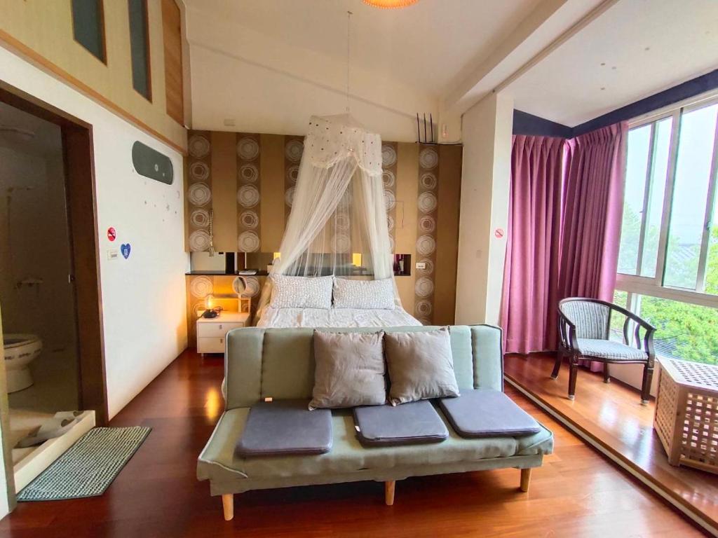 a bedroom with a bed and a couch in it at Miaoli Sanyi Travelling Homestay in Sanyi