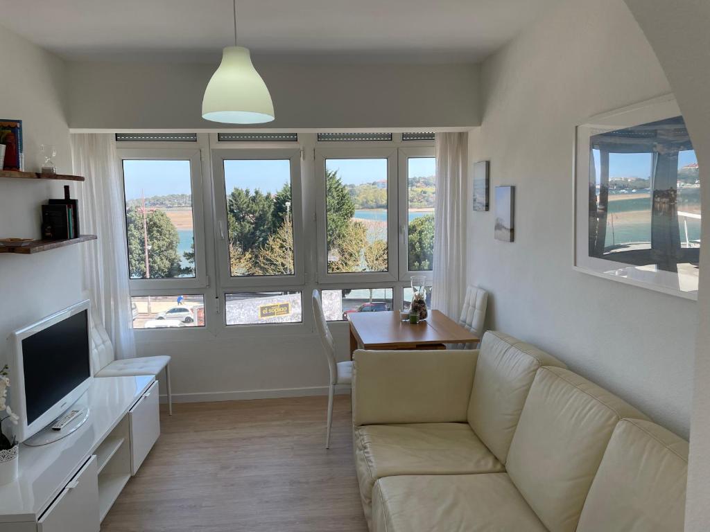 sala de estar con sofá, mesa y ventanas en Apartamento Excelentes vistas a la Ria, Wifi y Parking, en San Vicente de la Barquera