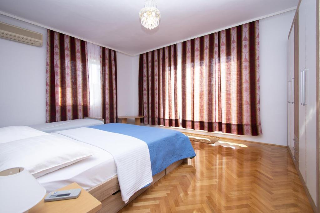 Schlafzimmer mit einem Bett und einem Fenster mit Vorhängen in der Unterkunft Apartment Monika in Šibenik