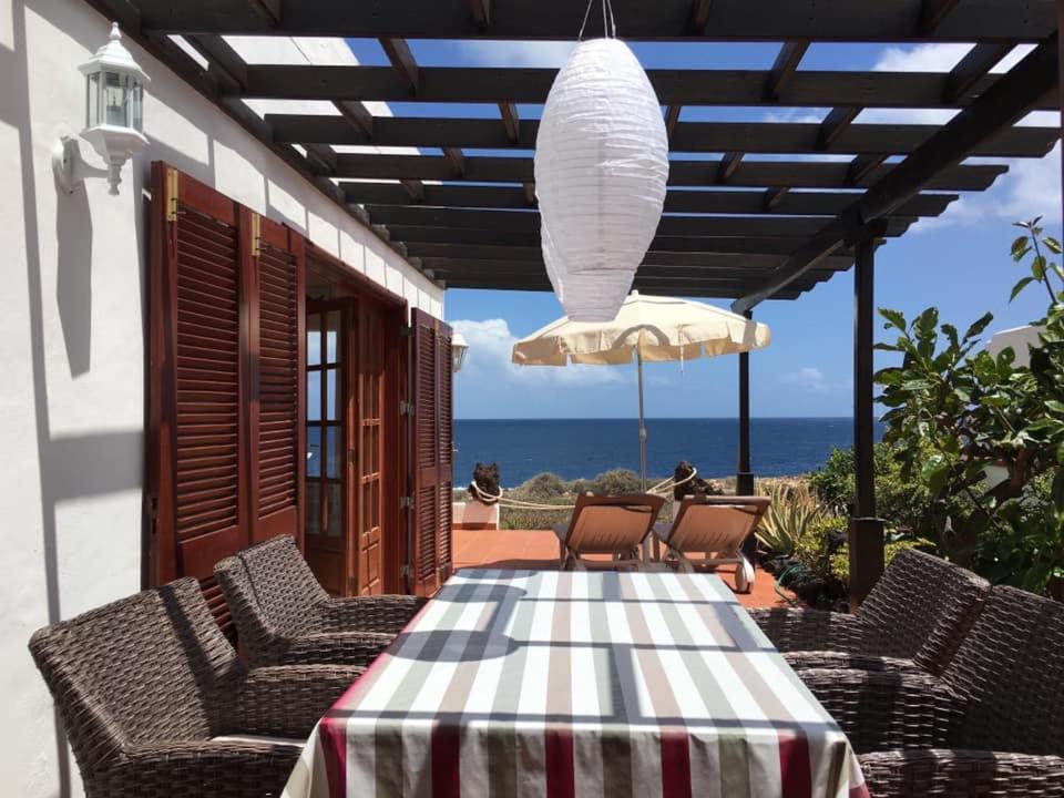 un patio con una mesa con sillas y una sombrilla en Paz del Mar en Charco del Palo