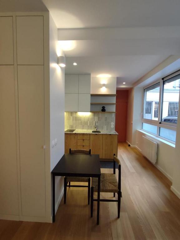 une salle à manger avec une table et une cuisine dans l'établissement Suite confortable sur le canal Saint-Martin / République, à Paris