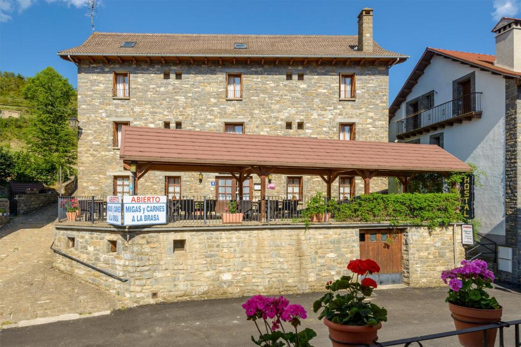 a large brick building with a balcony in front of it at Hostal Kimboa in Ansó