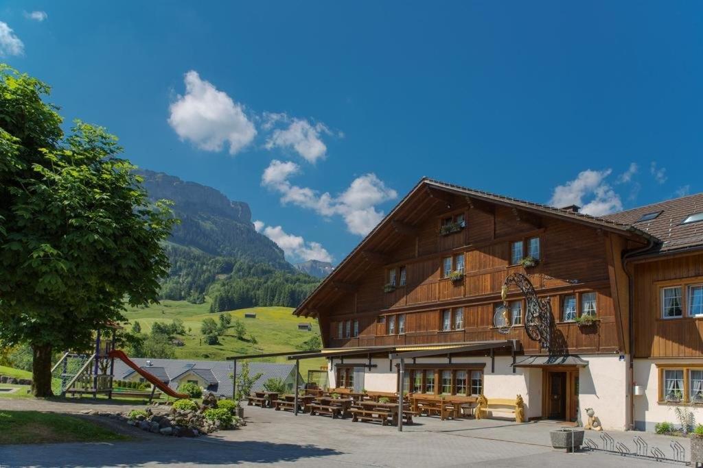 ein großes Holzgebäude mit Tischen und Bänken davor in der Unterkunft Gasthaus Rössli in Brülisau