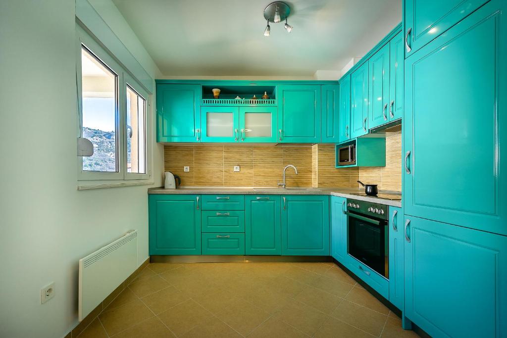 eine grüne Küche mit blauen Schränken und einem Waschbecken in der Unterkunft Apartments Green May in Budva