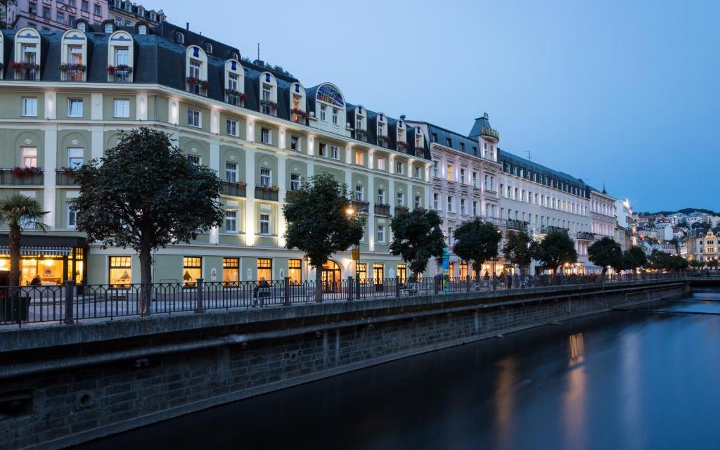 uma linha de edifícios junto a um rio em Hotel Kolonada em Karlovy Vary