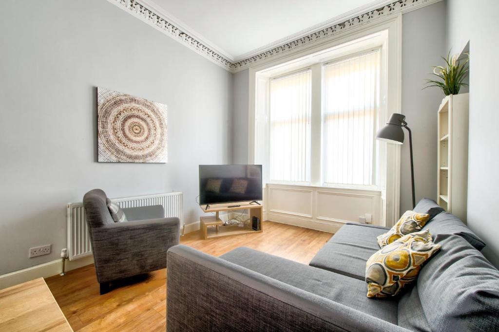 a living room with a couch and a television at Edinburgh City Central Apartment Sleeps 6 Free Parking in Edinburgh