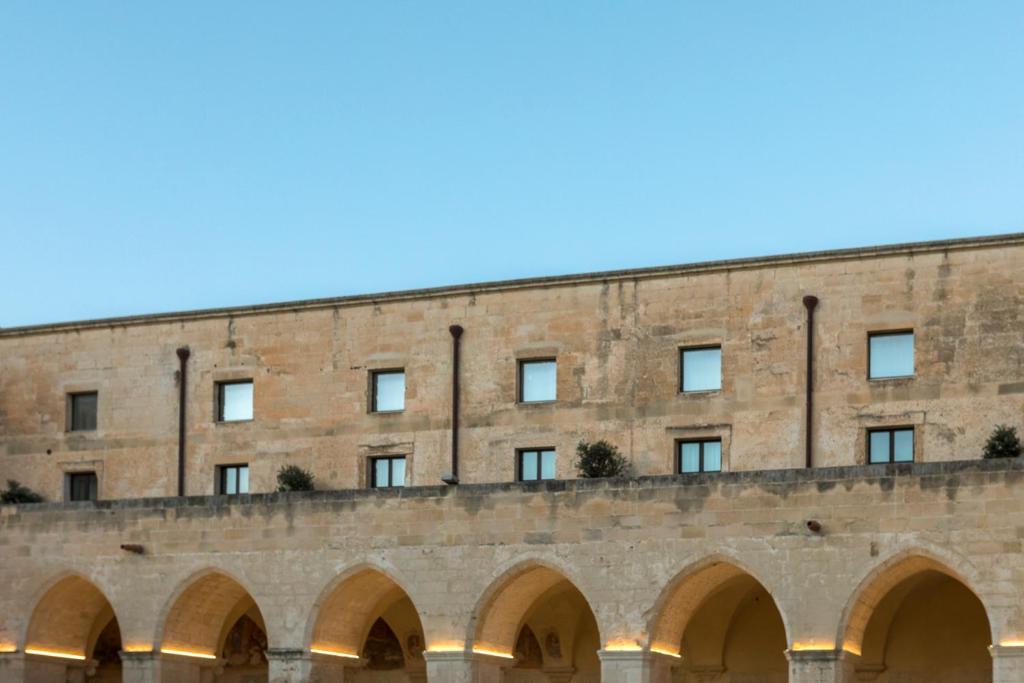 un grand bâtiment en briques avec des arches devant lui dans l'établissement Chiostro dei Domenicani - Dimora Storica, à Lecce