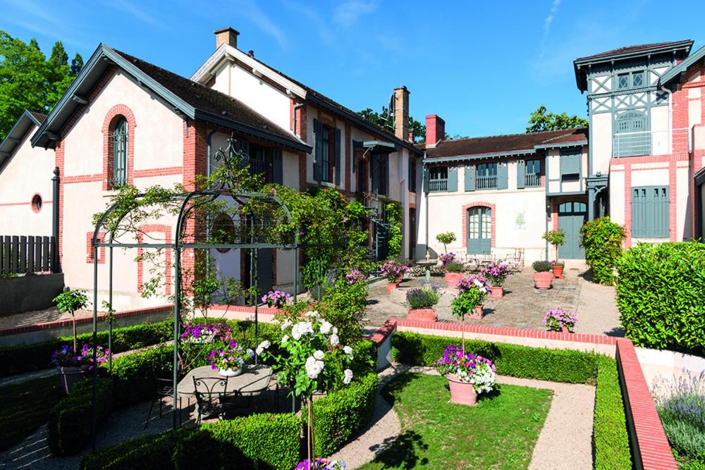 un jardin avec des fleurs en face d'une maison dans l'établissement Guesthouse Domaine du Chalet, à Chigny-les-Roses