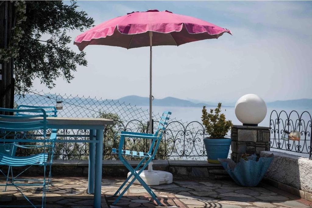 różowy parasol i dwa krzesła oraz stół ze stołem i stołem z w obiekcie Panoramic sea & mountain view villa w mieście Afissos