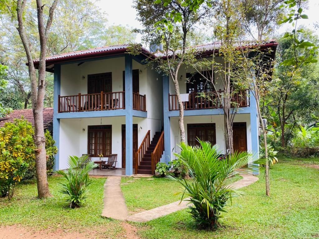 a house in the middle of a yard with trees at Isanka Lion Lodge in Sigiriya