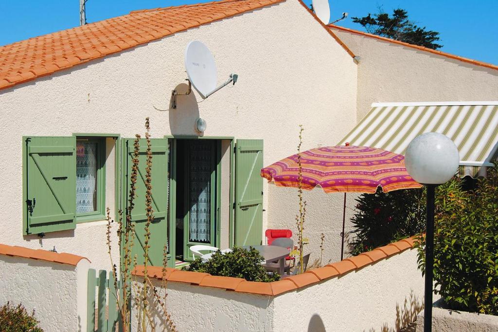 une maison avec un parasol, une table et des chaises dans l'établissement Holiday house near beach, St Denis-d'Oléron, à La Michelière