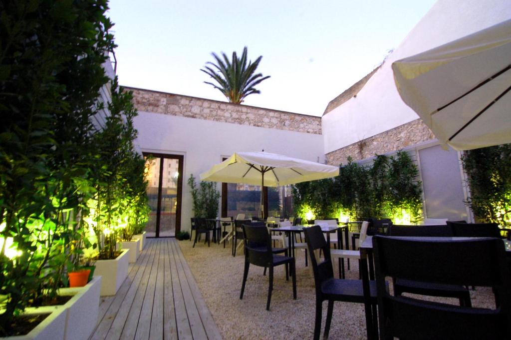 un restaurante con mesas, sillas y sombrilla en LoL Hostel Siracusa, en Siracusa