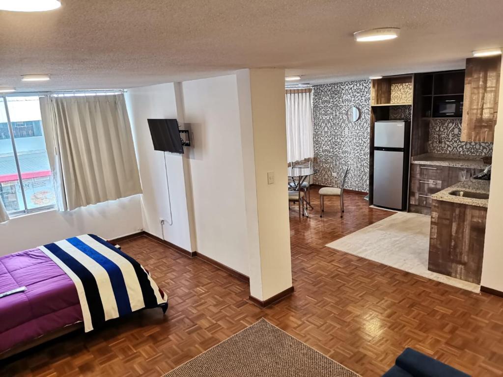 a hotel room with a bed and a kitchen at Suite Estudio in Quito