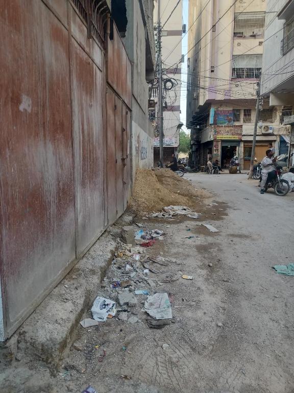 een vuile straat met afval aan de zijkant van een gebouw bij New Hotel Couple In Karachi in Karachi