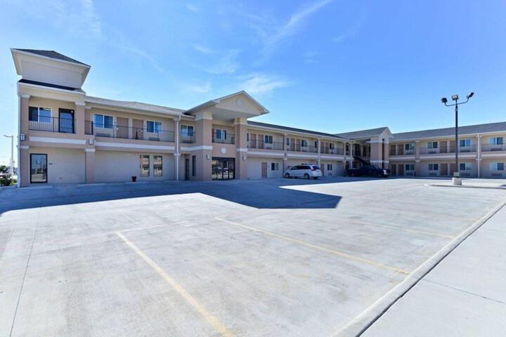 a large building with a car parked in a parking lot at Western Inn & Suites in Carrizo Springs