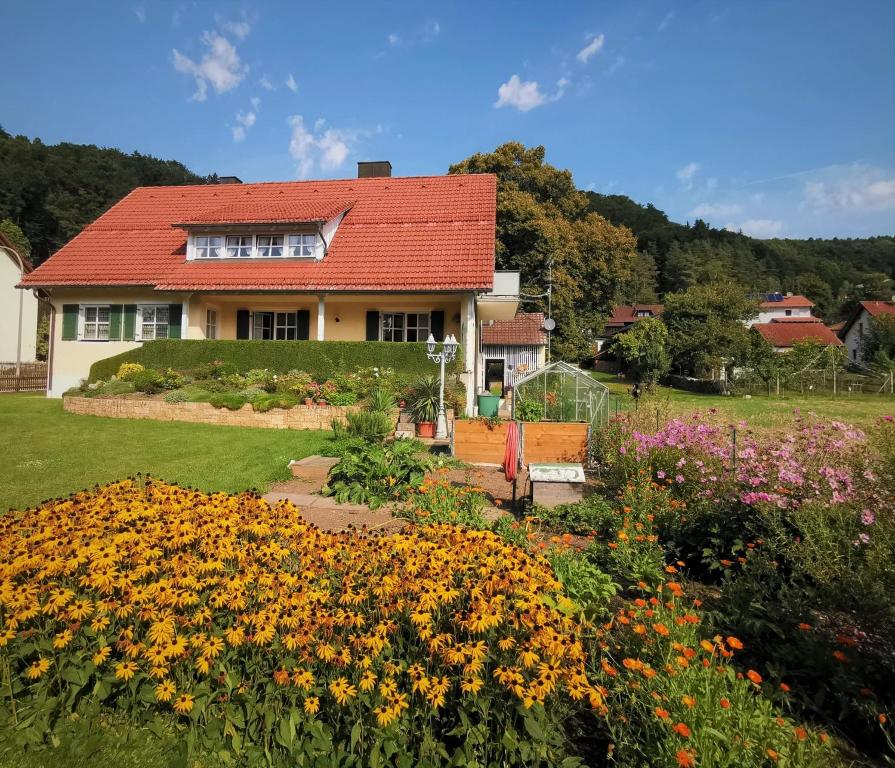 a house with a garden with flowers in the foreground at Ferienwohnung Agnes Mayer in Riedenburg