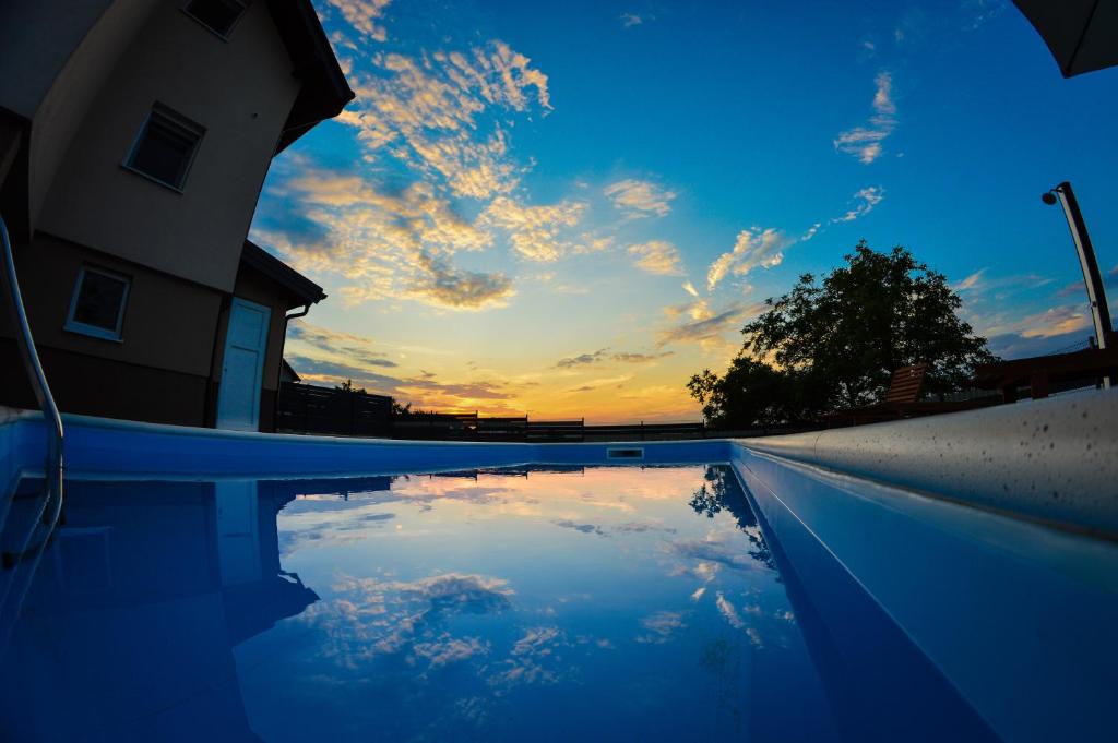 un reflet du ciel dans une piscine au coucher du soleil dans l'établissement Holiday Home Gračec, à Gračec