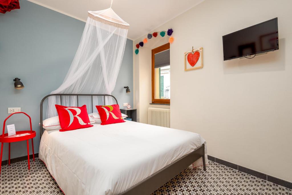 Schlafzimmer mit einem Bett mit roten Kissen und einem TV in der Unterkunft Carugio Remilde in La Spezia