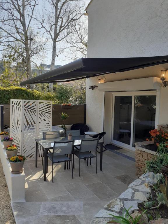 a patio with a table and chairs and an umbrella at Gite La vallée du silence in Le Beausset