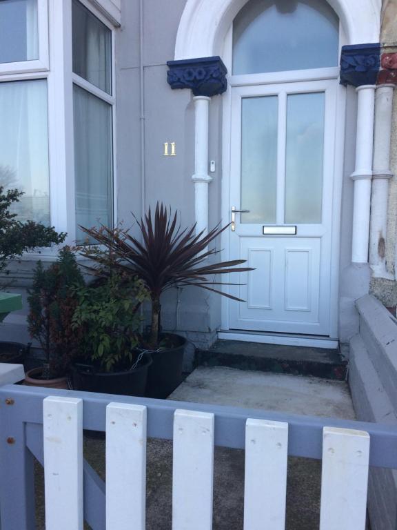 a white door of a house with plants in front at Lovely little flat by the sea in Cleethorpes in Cleethorpes