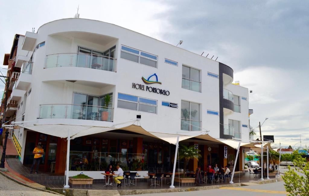 a white building with people sitting outside of it at Hotel Portobelo Guatape in Guatapé
