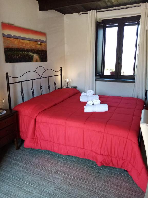 a bedroom with a red bed with two towels on it at La Giara B&B in San Demetrio Corone