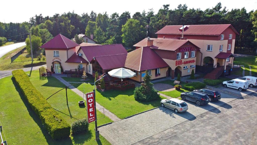 a large house with cars parked in a parking lot at Motel Łasuch in Osjaków