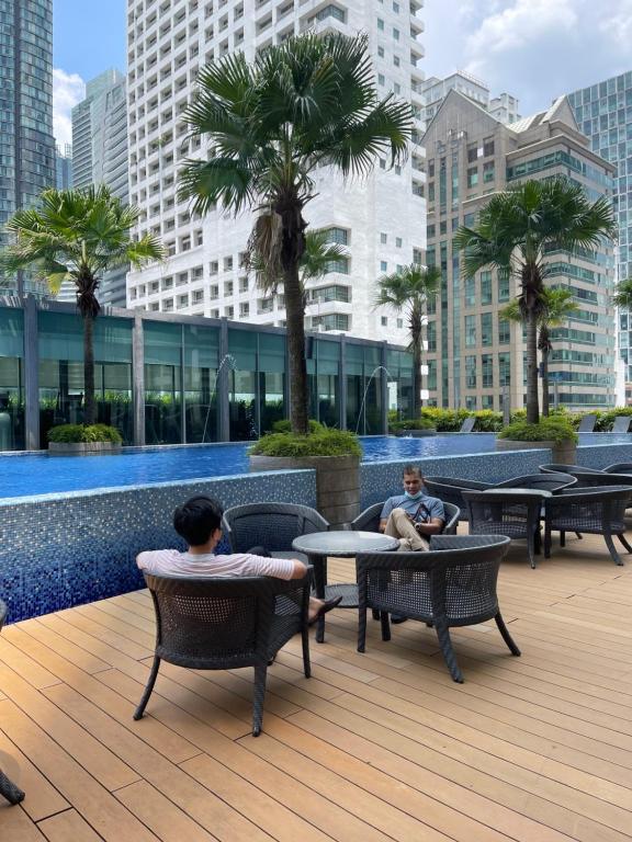 two men sitting in chairs on a patio in a city at Vortex Suites KLCC by Luna in Kuala Lumpur