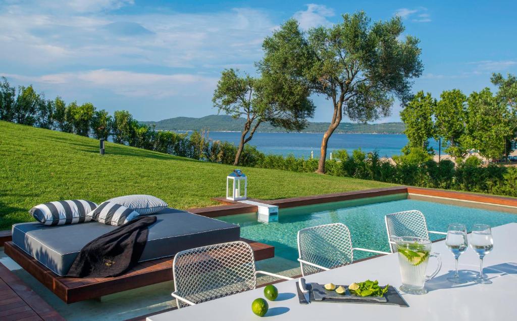 a villa with a pool and a table and chairs at Avaton Luxury Beach Resort - Relais & Chateaux in Ouranoupoli