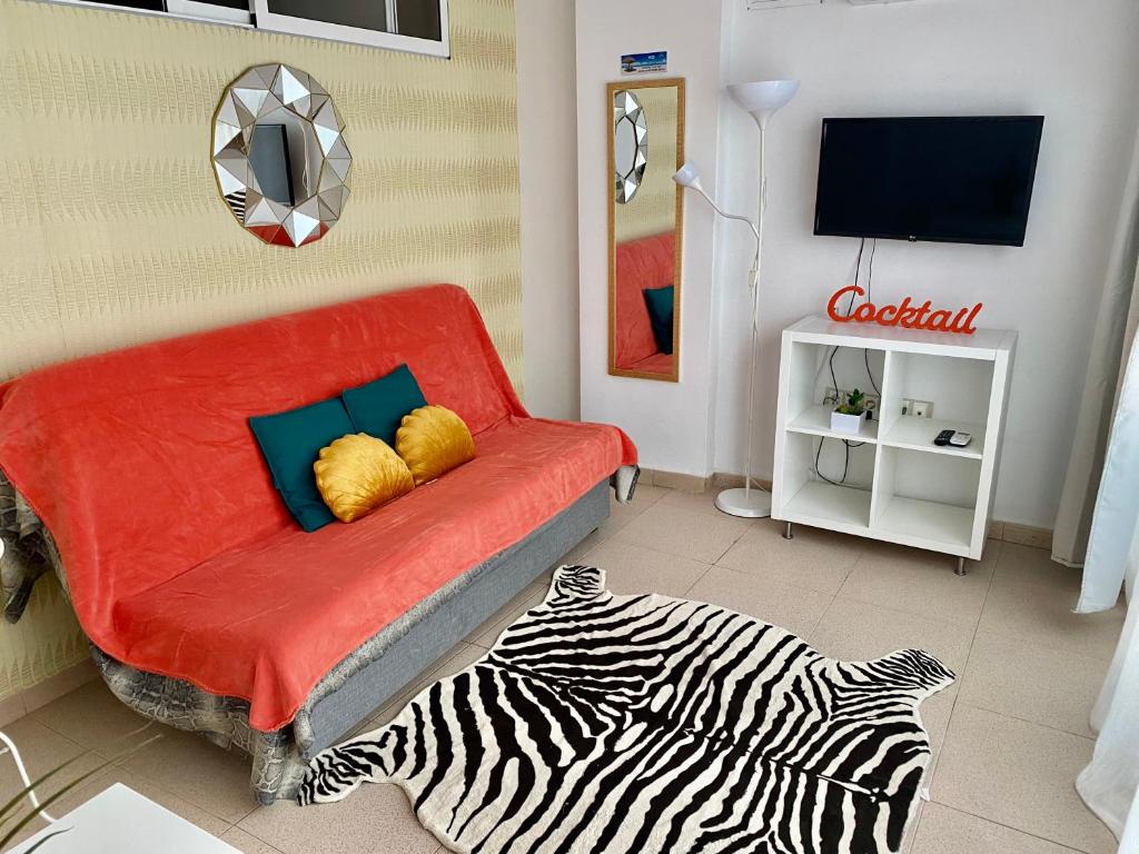uma sala de estar com um sofá vermelho e um tapete de zebraebra em MY SUNNY PAYMA BEACH Apartment em Benidorm