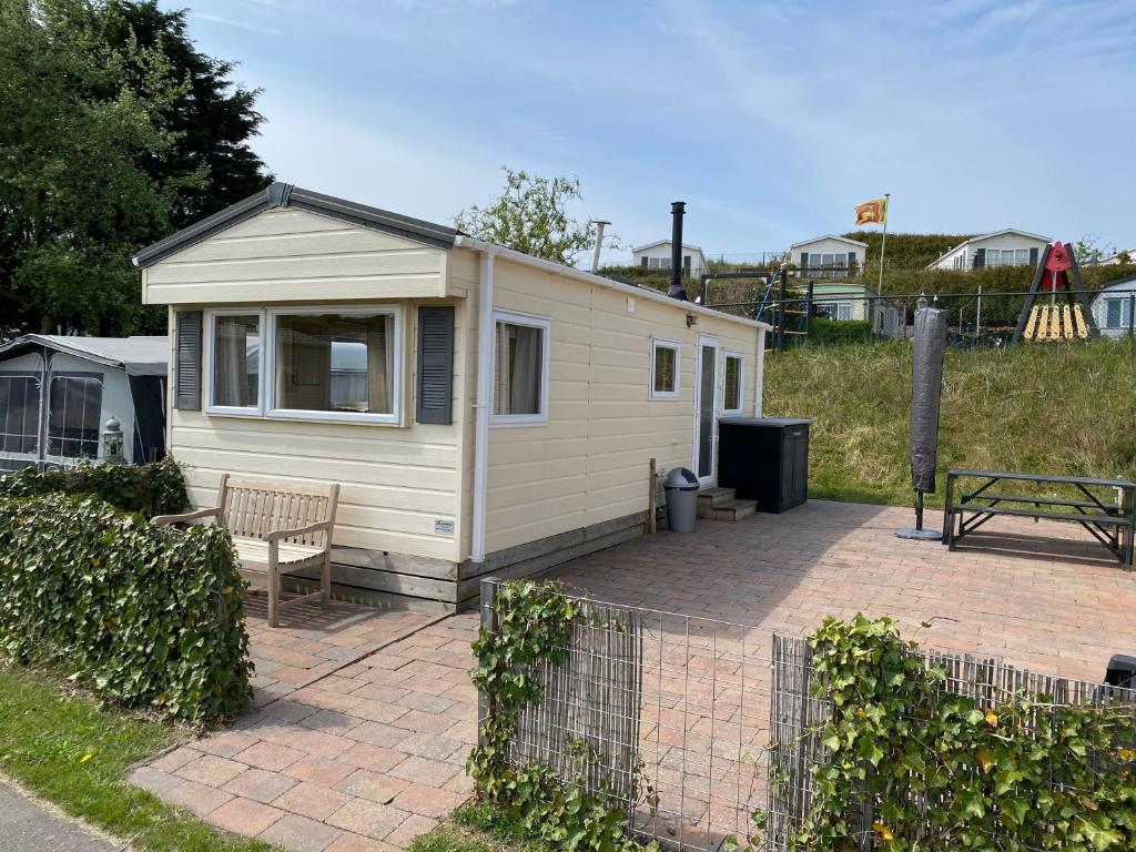 a small white cabin with a bench on a patio at Chalet Formentera in de duinen van IJmuiden aan Zee in IJmuiden