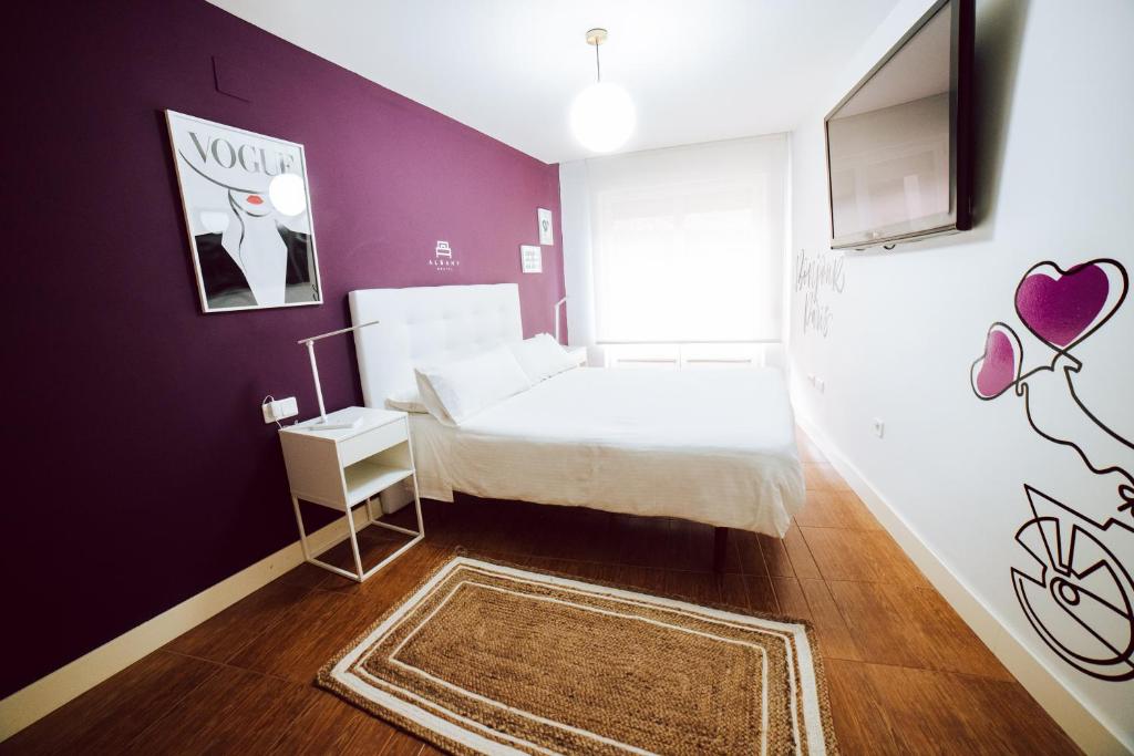 a bedroom with a white bed and a purple wall at Hostal Pozo in León