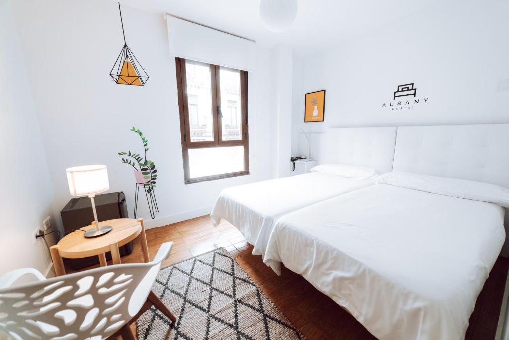 a white bedroom with a bed and a chair at Hostal Misericordia in León