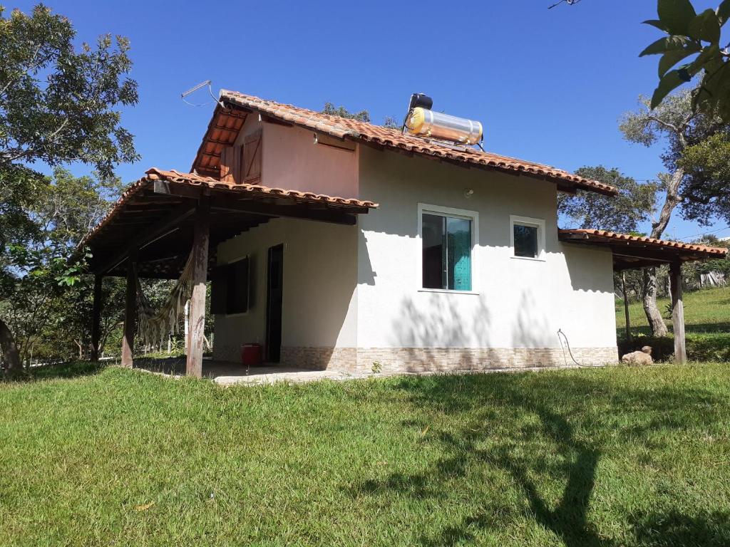 a small white house with a grass yard at Chalés paradise - Família in Serra do Cipo