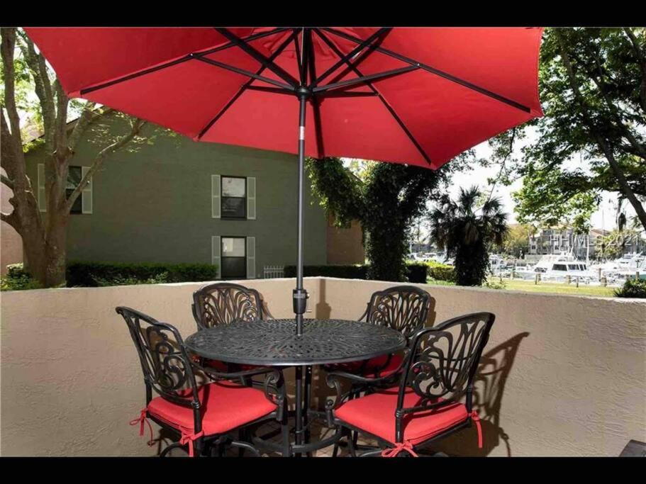 a black table with chairs and a red umbrella at In the Heart of Harbour Town 2BR 2BA Pool Access Close to Beach in Hilton Head Island