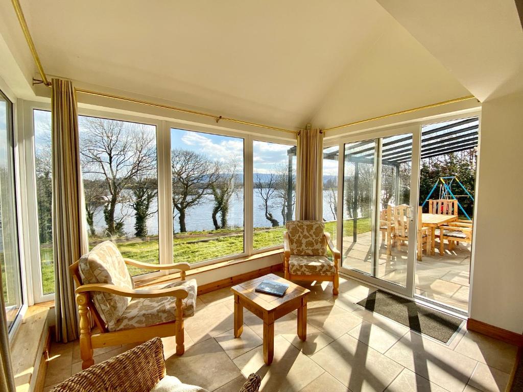 ein Wohnzimmer mit großen Fenstern und einem Tisch in der Unterkunft Shamrock Cottage in Aghnablaney
