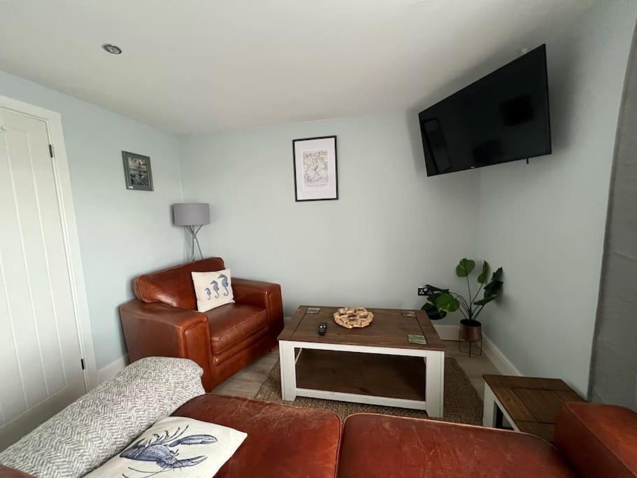 a living room with a couch and a tv and a chair at Orchard Lodge -Coastal Retreat, new build, village views, private garden and terrace in Saint Brides Major