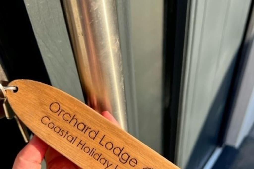 a person holding a wooden spoon with the words oakfield lodge cocktailhough at Orchard Lodge -Coastal Retreat, new build, village views, private garden and terrace in Saint Brides Major