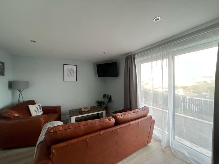 a living room with a couch and a large window at Orchard Lodge -Coastal Retreat, new build, village views, private garden and terrace in Saint Brides Major