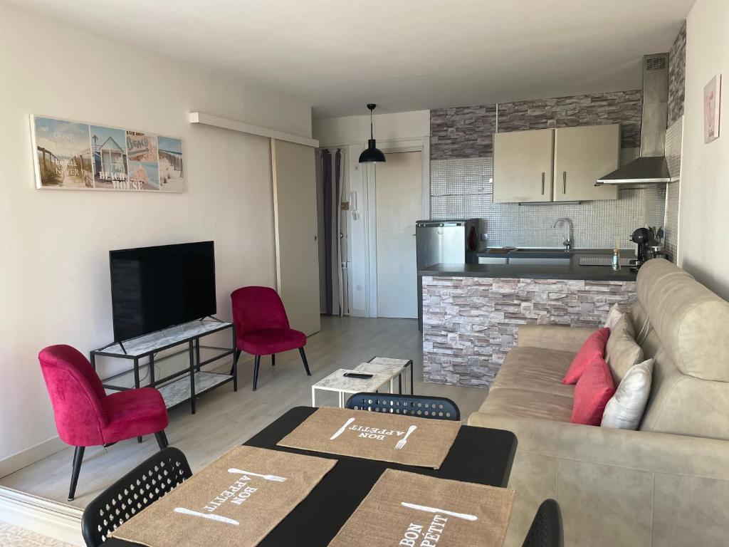 a living room with a couch and a kitchen at APPARTEMENT LUMINEUX SUR LE PORT! 5 MN DE LA PLAGE AVEC PARKING PRIVE in Cap d'Agde