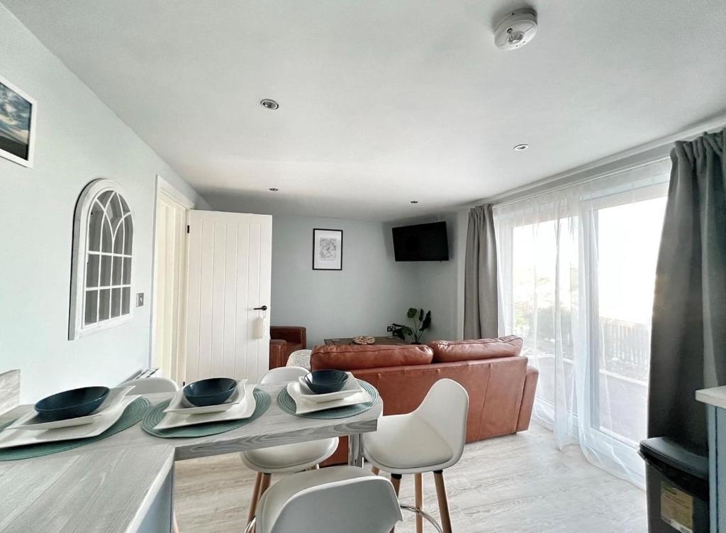 a living room with a couch and a table and chairs at Orchard Lodge -Coastal Retreat, new build, village views, private garden and terrace in Saint Brides Major