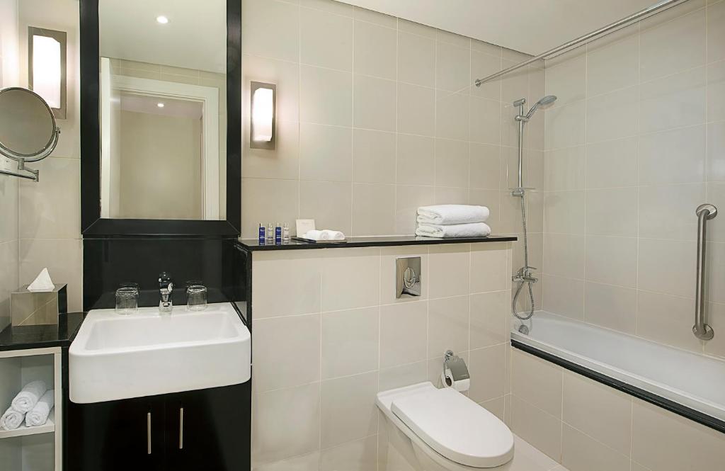 a white bathroom with a sink and a toilet at DAMAC Maison Canal Views in Dubai